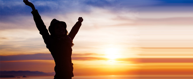 silhouette of woman with arms outstretched at sunrise