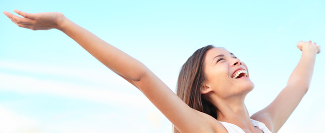 Smiling happy woman with arms outstretched and looking upwards