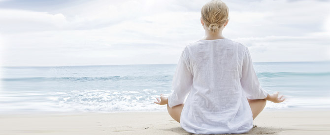 woman in white meditating at seashore