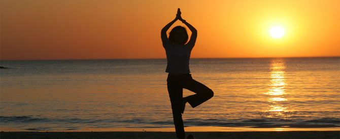 woman silhouette doing yoga on the beach at sunrise