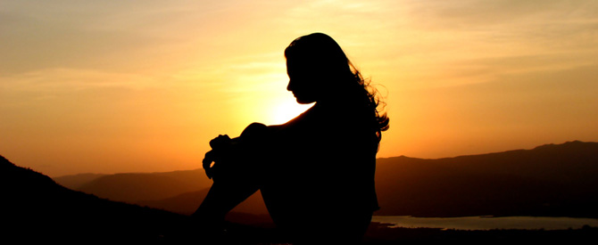 sitting woman silhouette with sunset background