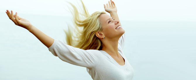 Happy, blonde woman with arms outstretched and looking up.
