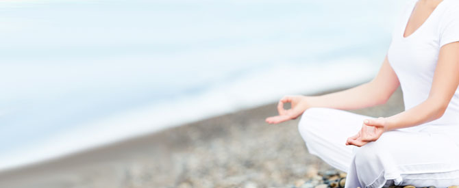 woman in white meditating on the beach