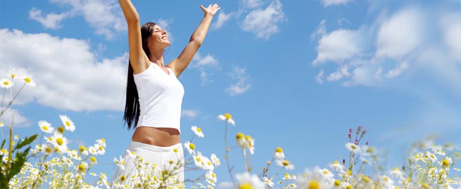 Happy woman wit hands up in a field of flowers.