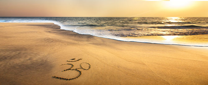 Inspirational sunset on the beach with Om etched in the sand.