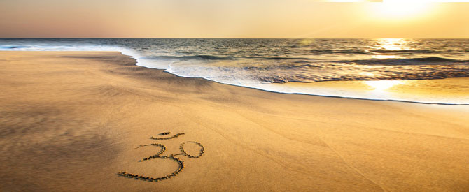 Inspirational sunset on the beach with Om etched in the sand.