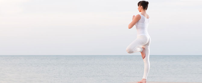 woman doing yoga by the seaside with hands in the prayer position.