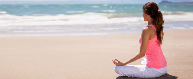 woman meditating on a sunny day at the beach.