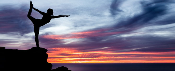 Silhouette-of-woman-in-yoga-pose-at-edge-of-a-cliff