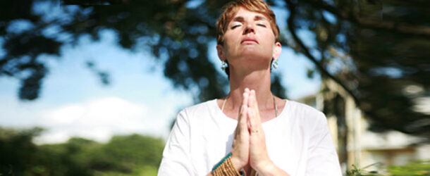woman with hands in prayer looking upwards in devotion