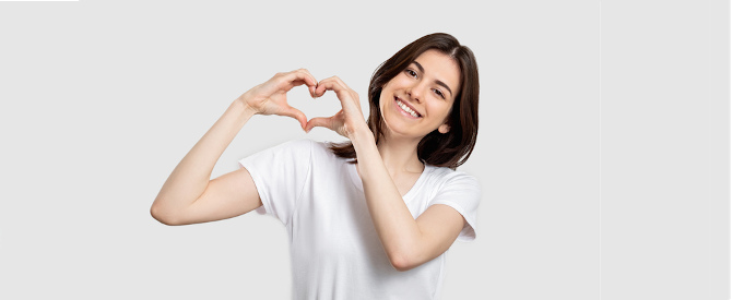 Happy woman showing heart gesture on neutral background