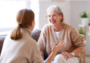 Young woman giving her attention to an older woman while sitting on a sofa