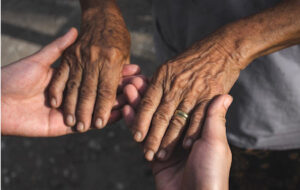 Young woman hands holding elderly person's hands.