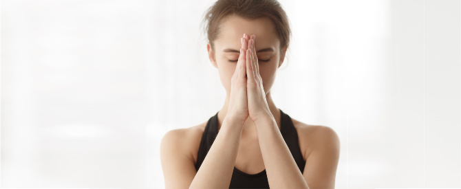 woman with eyes closed and hands in prayer