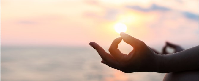 closeup of hand mudra in meditation on the beach at sunset