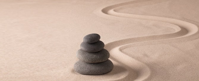 Balancing blak rocks in zen sand garden