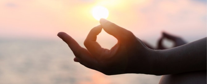 Silhouette of woman’s hands in chin mudra while showing how to recite a mantra.