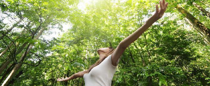woman with arms outstretched among the trees showing that she is a member of the cosmic family