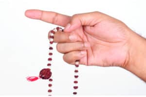 Hands holding a rosary. Chanting the holy names of God using a rosary is practising the yoga of devotion.