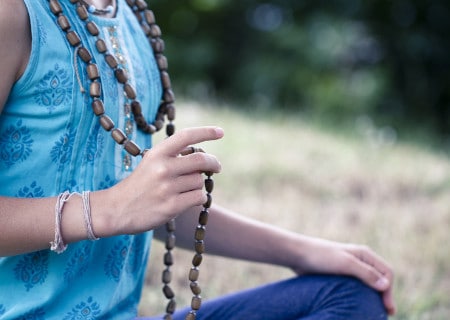 woman chanting a mantra with beads as a means to overcome obstacles in meditation