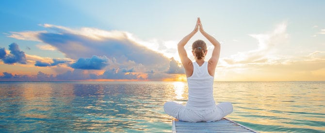 woman siting at the end of a jetty overlooking waves in the water representing obstacles in meditation