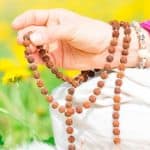 Hands holding a mala while doing japa, the repetition of a divine name