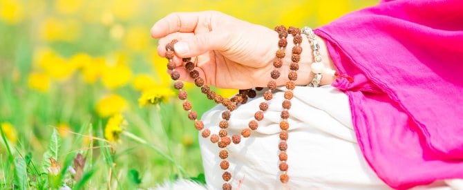 Hands holding a mala while doing japa, the repetition of a divine name