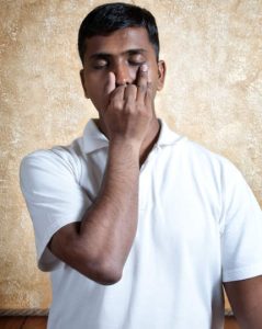 Man doing alternate nostril breathing pranayama with nasika mudra