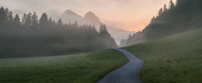 Serene path leading to distant mountains at dawn representing your spiritual journey.