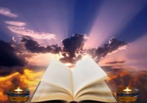 Holy book open with mauve sun rays in sky in the background