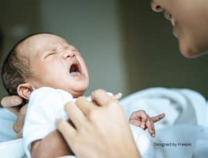 Newborn baby crying while mother smilies