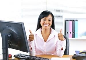smiling working woman at desk with thumbs up showing how spirituality for young people brings a positive mindset