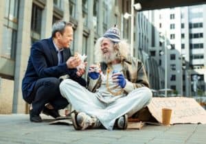 Smiling executive showing kindness to a homeless person indicating his inner maturity