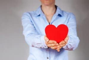 Woman holding a red heart showing compassion and forgiveness, signs of inner maturity
