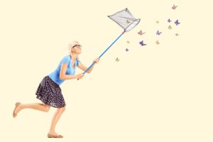 Woman chasing butterflies with a net showing how vasanas keep us looking outside for happiness