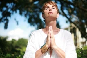 Woman with hands in prayer position seeking detachment from the world through atttachment to the divine