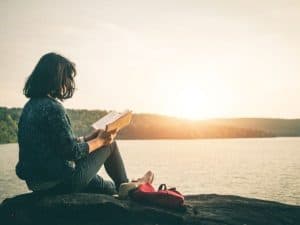 Woman sitting by water reflecting on living a spiritual life